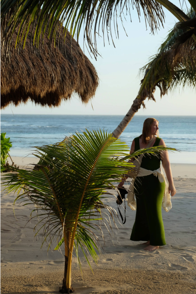 Photo of photographer, Daisy Sophia, posing with her camera on the beach while shooting PRANELLA Spring/Summer 2024 collection.